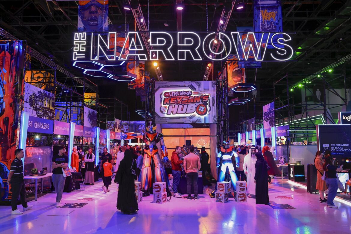 Visitors explore the vibrant Narrows Zone at GameExpo during the Dubai Esports and Games Festival 2025, surrounded by colorful LED displays, merchandise booths, and life-size gaming characters.