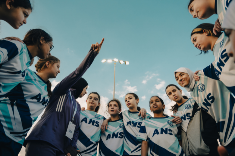 Girls' football team gathers in a motivational huddle before their final match at the Abu Dhabi School Sports Championship.