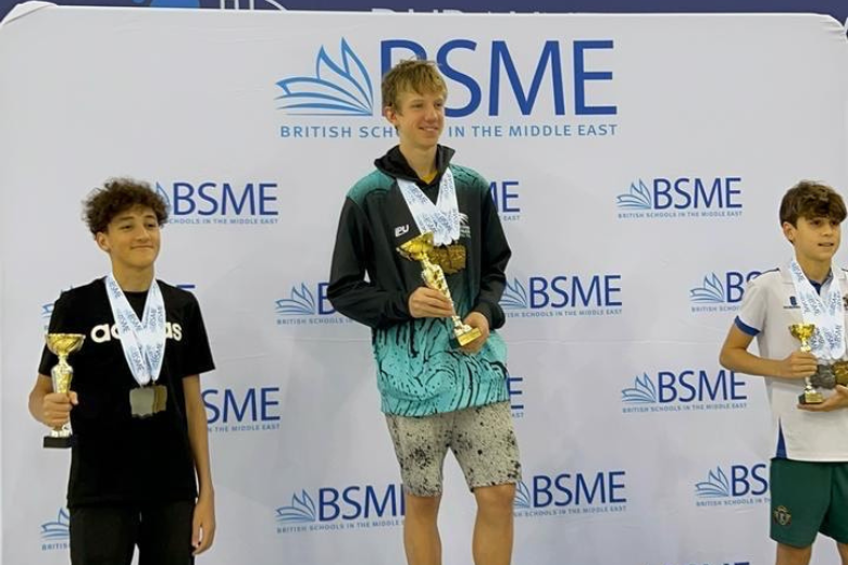 Adam Radwan, ICS Al Danah Year 9 swimmer, standing on the podium with fellow competitors at the BSME championship in Dubai.