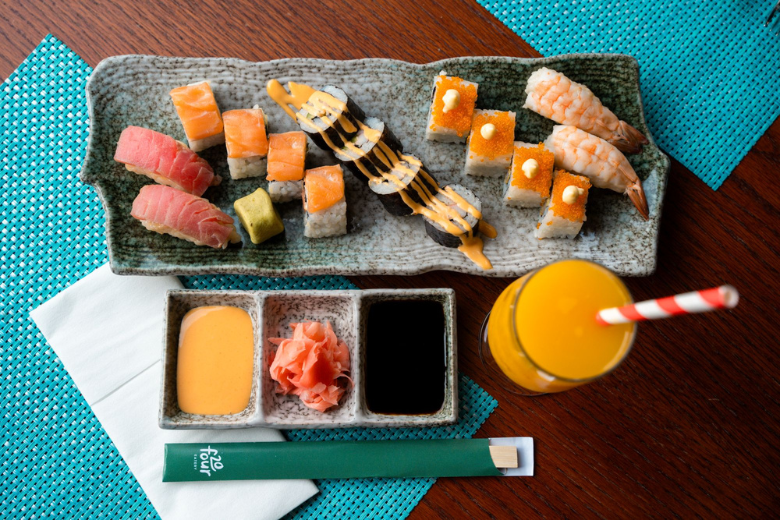A colourful sushi platter with soy sauce, wasabi, and a glass of orange juice at Wyndham Residences The Palm