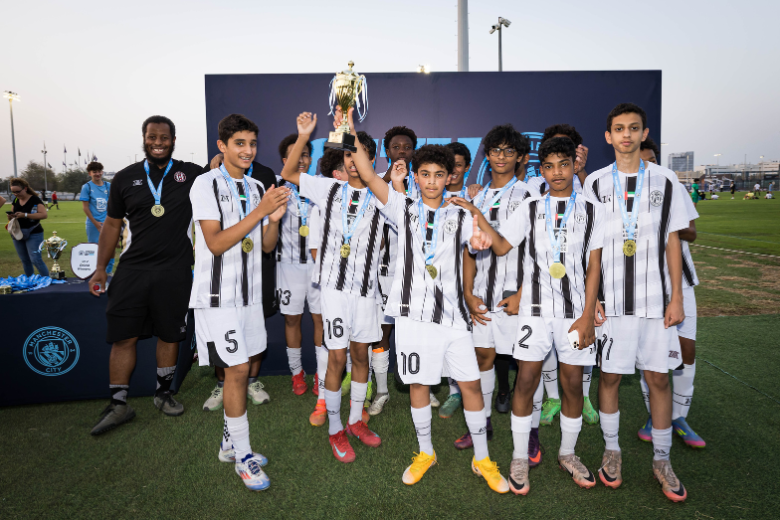 Al Jazira Club Academy players lifting a trophy after a successful tournament in the UAE, part of their elite youth football development.