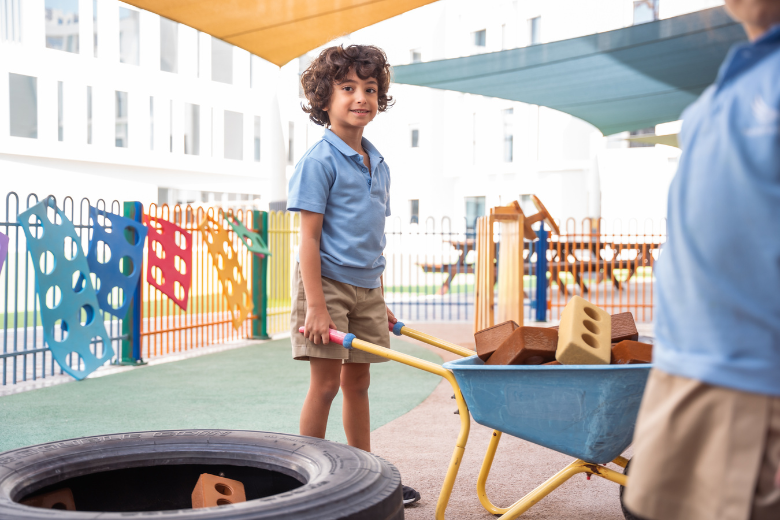 A child at The Aquila School engaging in outdoor learning with blocks and construction materials during EYFS.