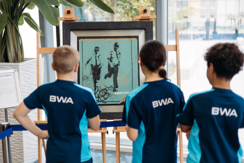 Bloom World Academy students observing Banksy's 'Running Coppers' artwork at the school’s art fair.
