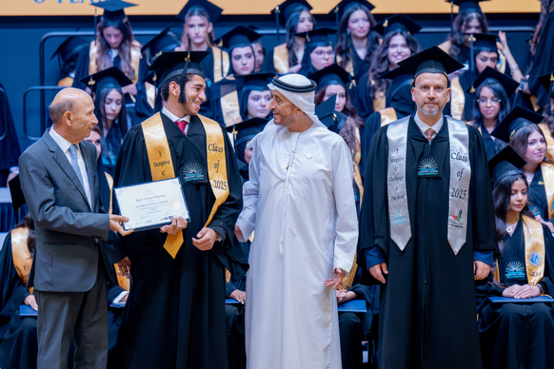 ICS graduate receiving a certificate on stage alongside school leaders and special guests during the 2025 ceremony.