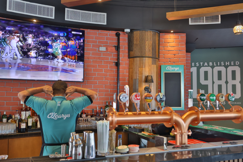 Interior of O’Learys Sports Bar with live sports on screen and signature drinks in Dubai Investment Park
