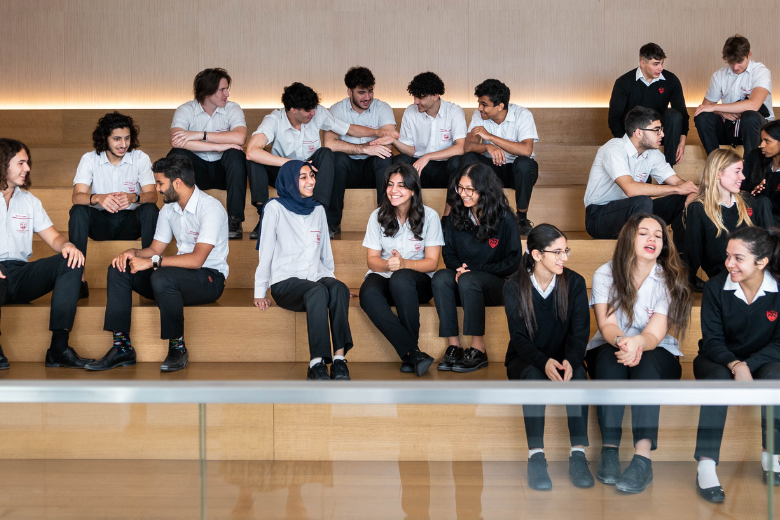 Sixth Form students at The English College, Dubai seated on wooden steps