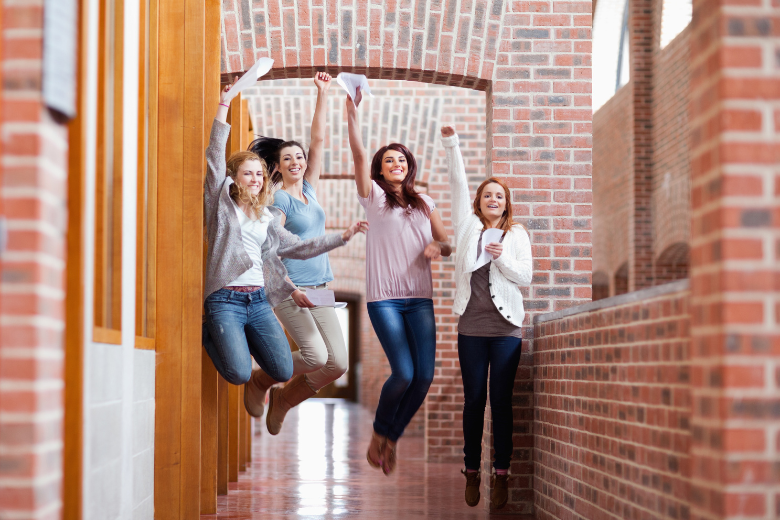 Group of high school students celebrating their exam results in a school hallway, symbolising student success and wellbeing.