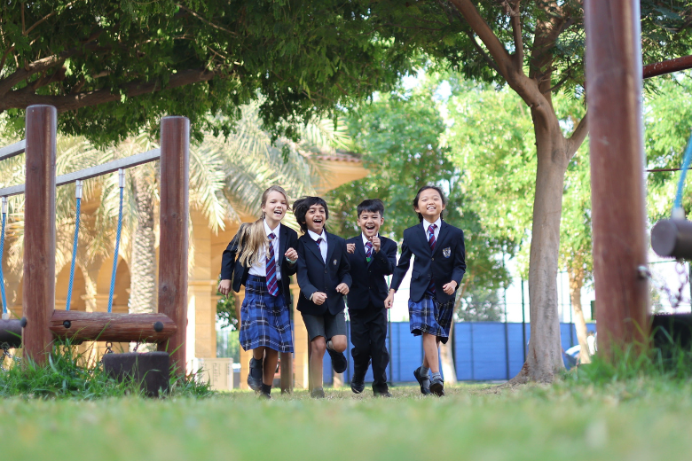 Brighton College Abu Dhabi pupils running happily in the outdoor playground.