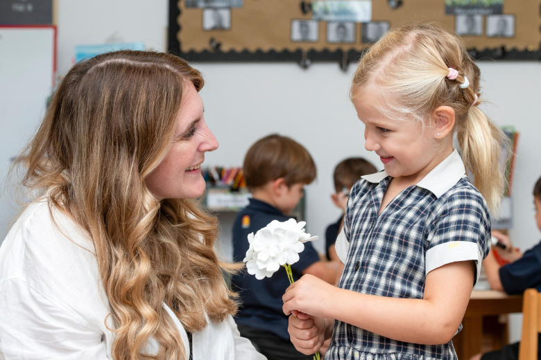 Teacher smiling with young pupil during class activity at Brighton College Dubai.