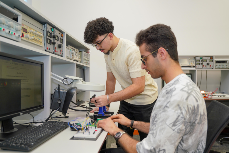 Two Canadian University Dubai students conducting engineering research in the lab.