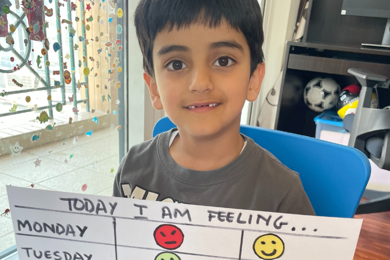 Child holding a daily emotions chart as part of a wellbeing activity at school in the UAE.