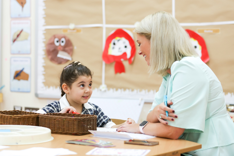 Brighton College teacher offering one-on-one support to a young student, demonstrating nurturing classroom-based pastoral care.
