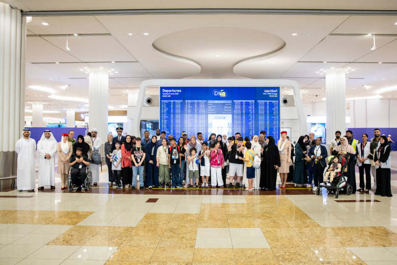 Group photo at DXB Terminal featuring families, caregivers, and Dubai Airports team participating in inclusive airport travel simulation.