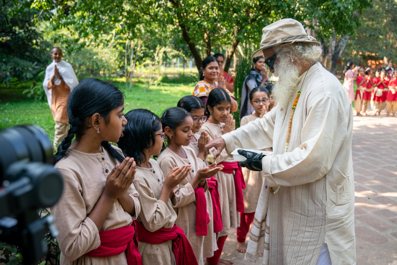 Sadhguru interacting with schoolchildren in a natural setting during an educational gathering