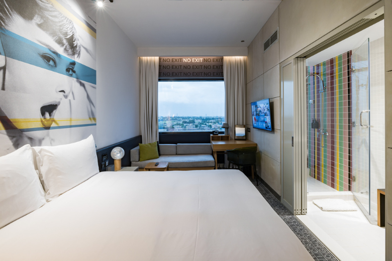 Stylish and modern Studio One Hotel room with city view and vibrant shower design
