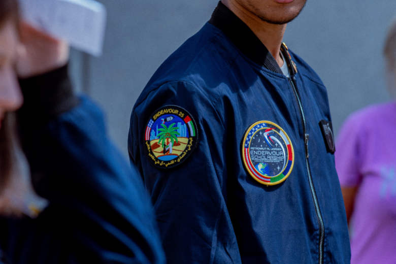 Close-up of ICS student wearing the Astronaut Al Worden Endeavour Scholarship flight jacket with mission patches.
