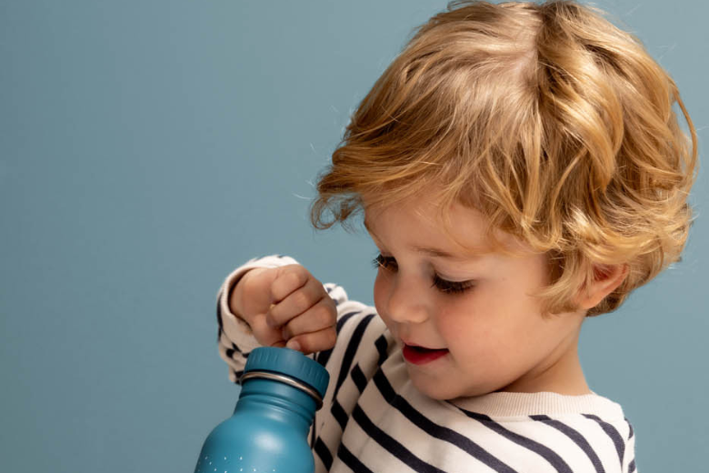 Young boy opening a blue reusable water bottle as part of Jashanmal’s Back-to-School 2025 collection.
