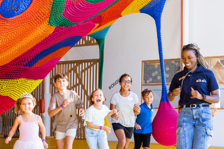 Children playing and running under the colourful crochet installation at Toshi’s Nets in OliOli® Dubai.