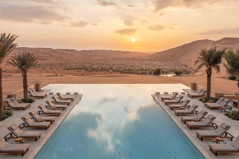 Infinity pool at Qasr Al Sarab Desert Resort overlooking the golden dunes at sunset.