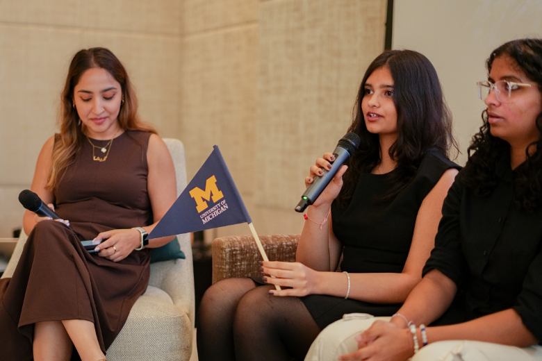 UAE student speaking during a US university panel holding a University of Michigan flag
