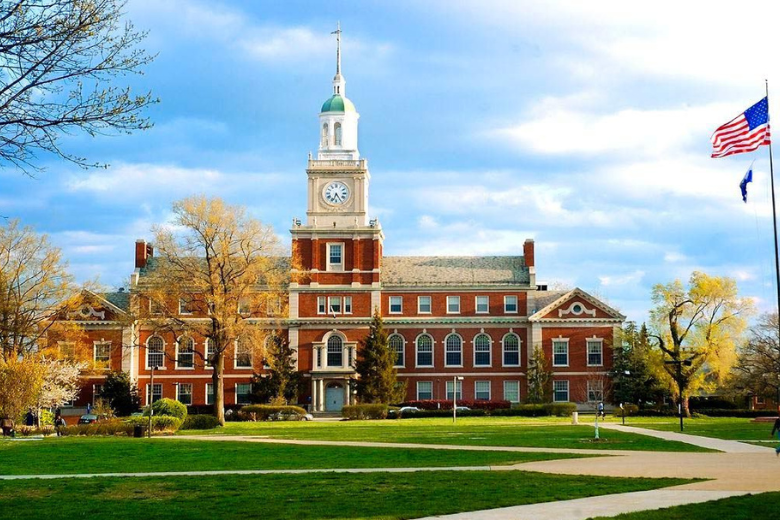 Historic US university campus building with American flag during spring season