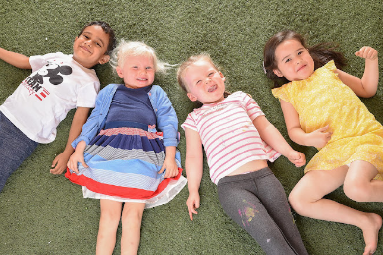 Children at Art Village Early Childhood Centre lying on grass, showcasing nature-inspired early learning.