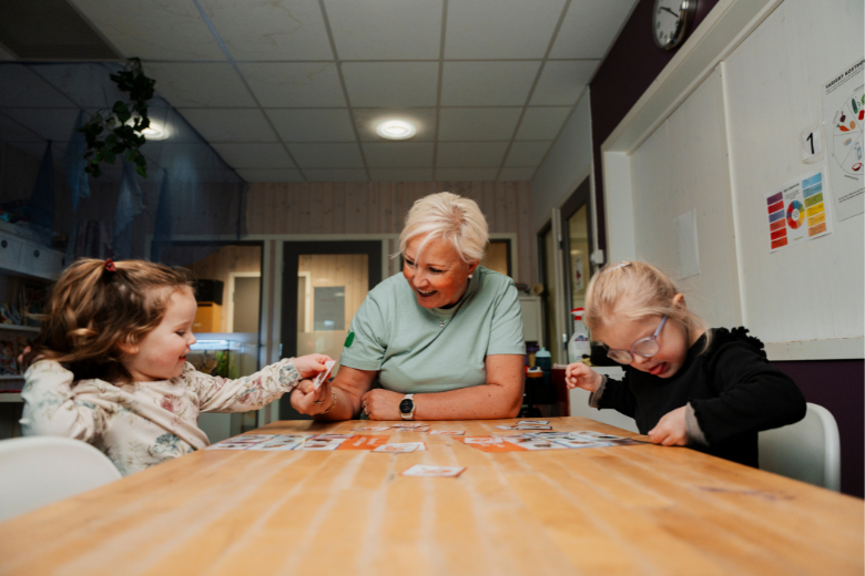 Teacher guiding children in a card activity at Dibber International Nurseries, supporting interactive and inclusive early learning