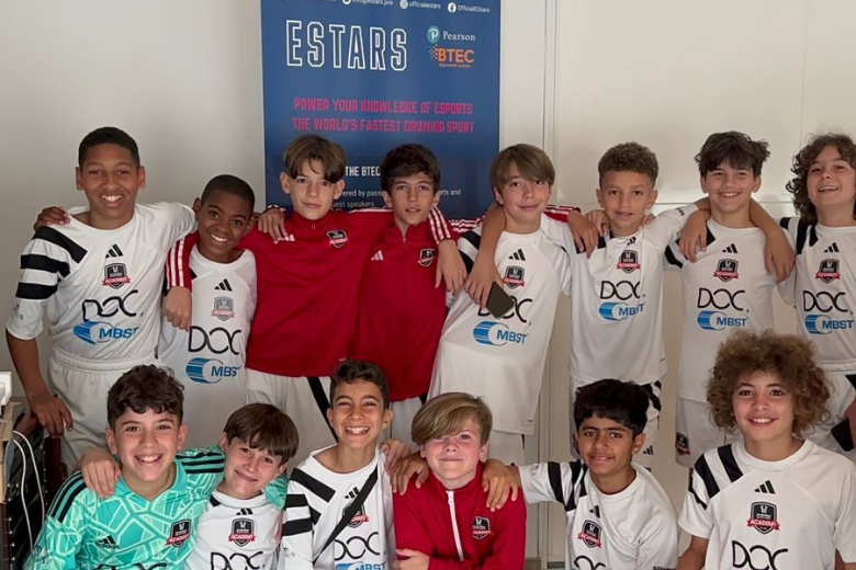 Youth football squad smiling in front of an EStars banner for the BTEC in esports