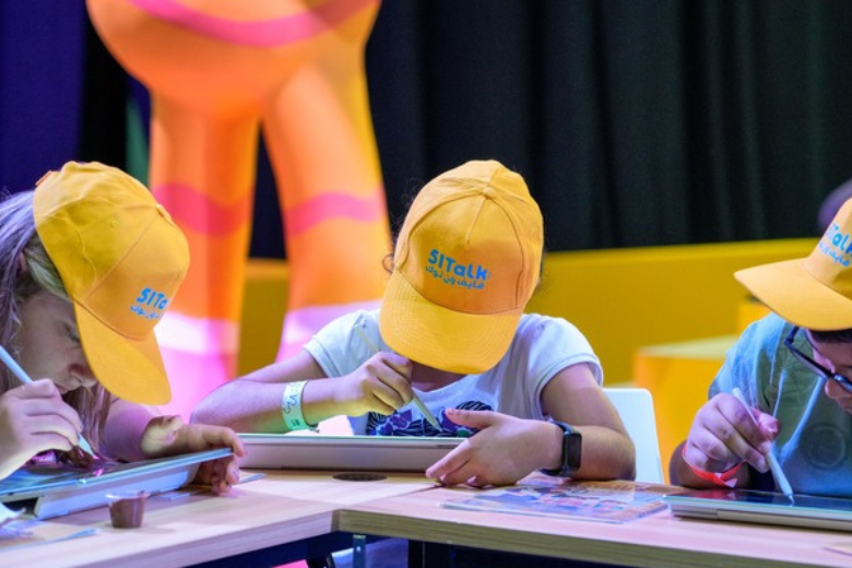 Students wearing 51Talk hats using Huawei tablets to explore interactive learning tools in the UAE.