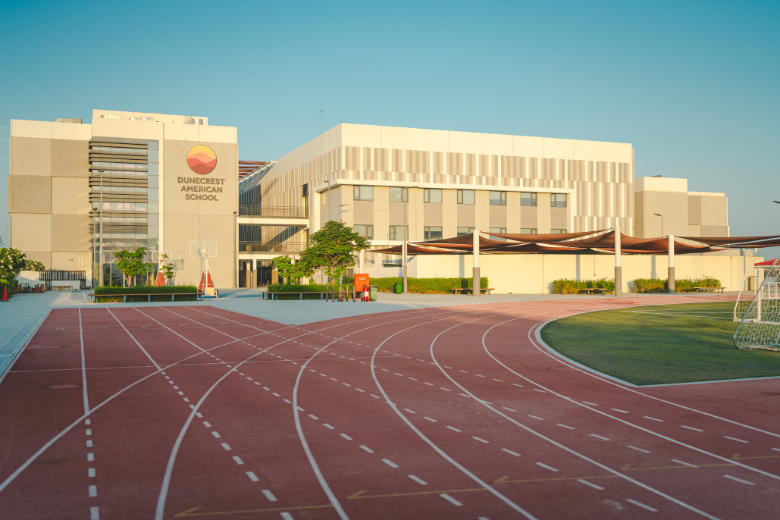 Exterior view of Dunecrest American School campus with athletics track and modern facilities