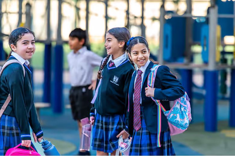 Group of children arriving at school with backpacks and greeting their friends