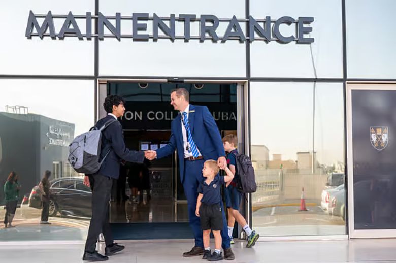 Children entering school gates in the morning as teachers welcome them back to campus