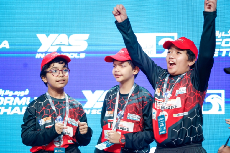 An excited student team stands together showcasing their matching motorsport uniforms and technical design portfolio
